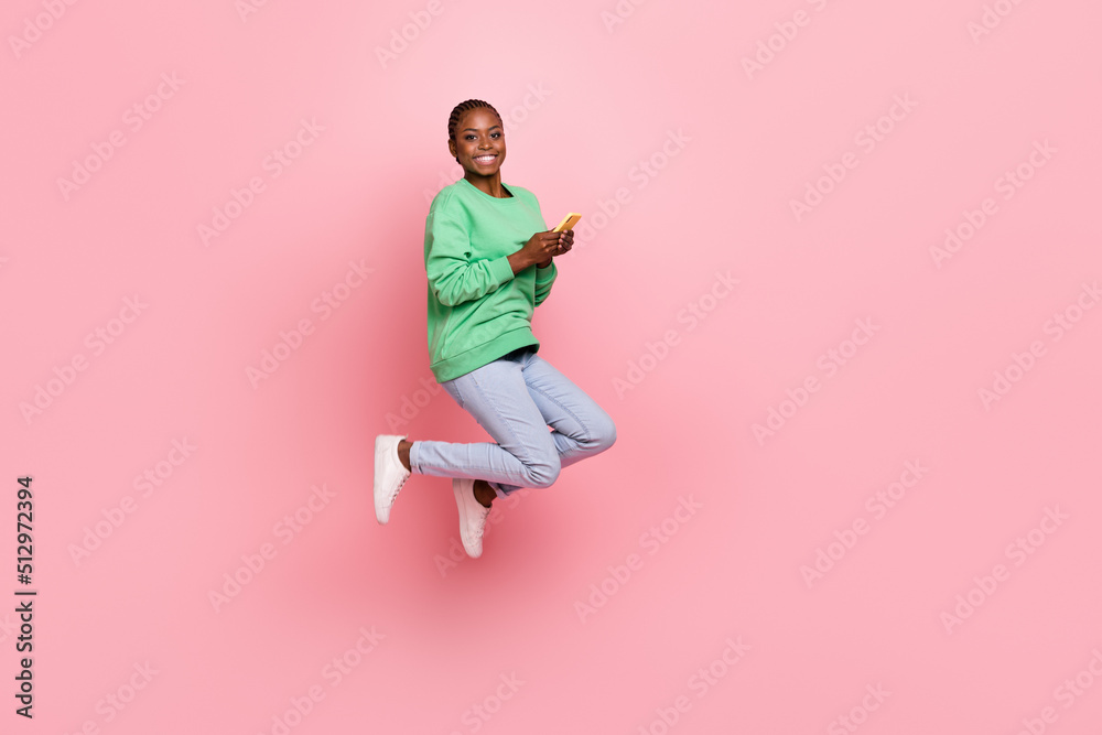 Full body portrait of carefree energetic girl jumping use telephone isolated on pink color background
