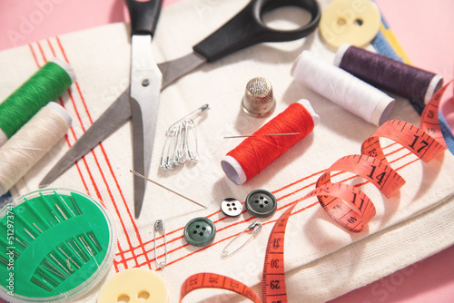 Sewing tools on the pink paper background.