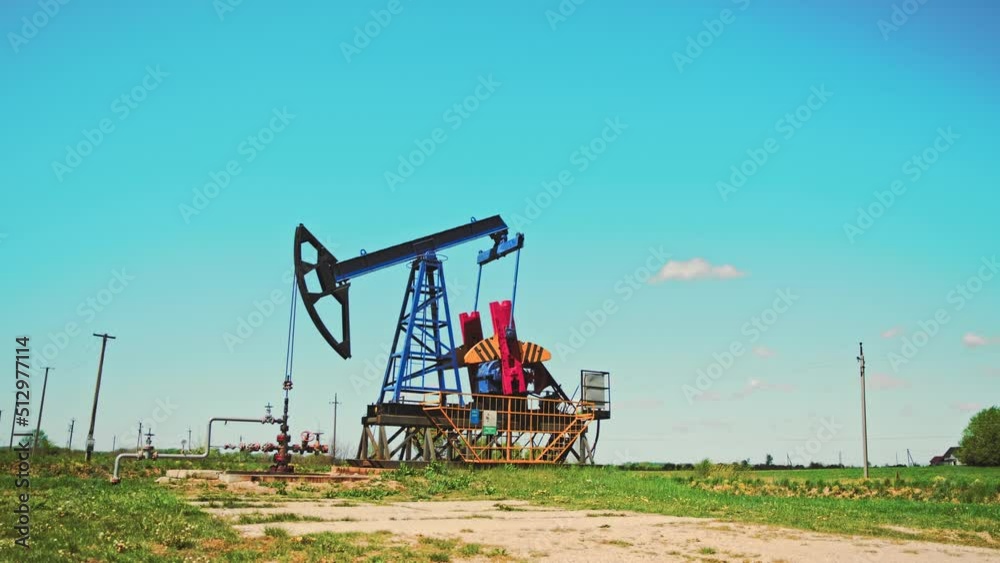 Medium shot of working oil pump rig at sunny day. Oil and gas production. Pump Jack are running. Drilling rigs for fossil fuel and crude oil production. Medium shot of working oil pump rig at sunny day. Oil and gas production. Pump Jack are running. Drilling rigs for fossil fuel and crude oil production.
