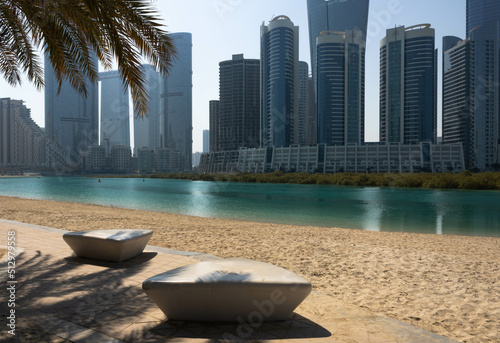 Al Reem Central park, beach walk with  stone benches and a palm tree, modern skyscrapers in the background,  Abu Dhabi photo