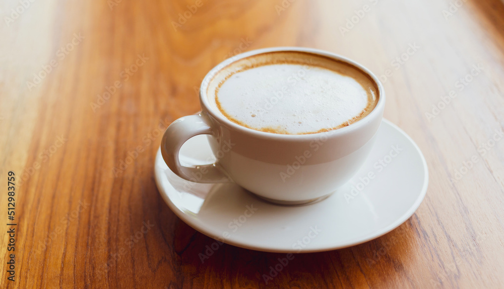 Cup of cappuccino coffee with a latte on a wooden bar in a sunlit cafe in the morning. Cup of cappuccino coffee with a latte on a wooden bar in a sunlit cafe in the morning.