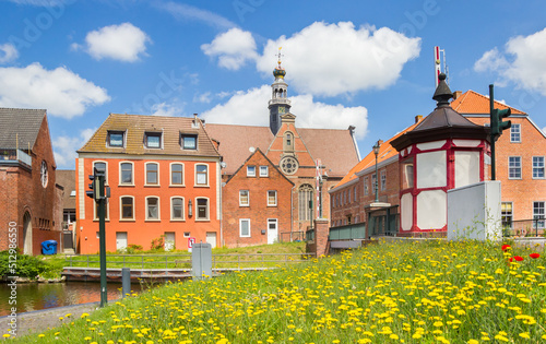 Canvastavla Yellow flowers in front of the historic new church in Emden, Germany