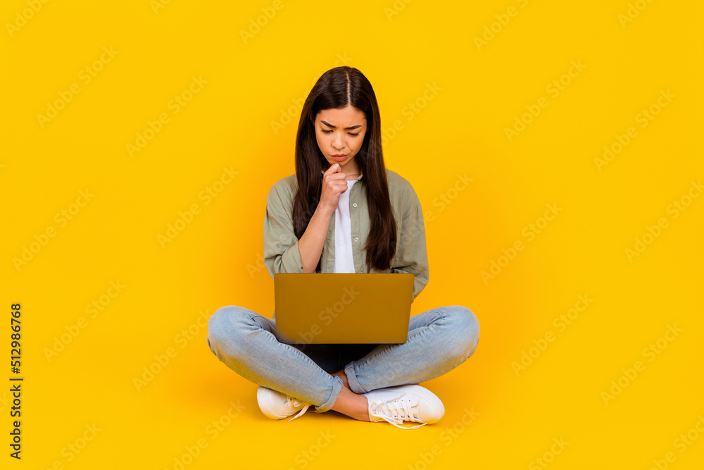 Full body photo of minded creative person arm touch chin use netbook write email isolated on yellow color background Full body photo of minded creative person arm touch chin use netbook write email isolated on yellow color background