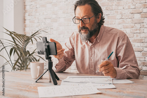 Foto Young mature man using mobile phone to record an online lesson for his channerl