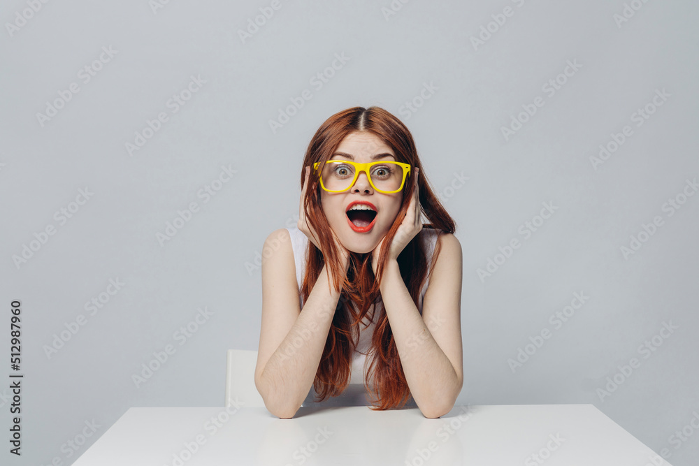 Surprised Caucasian woman sitting at table wearing yellow eyeglasses