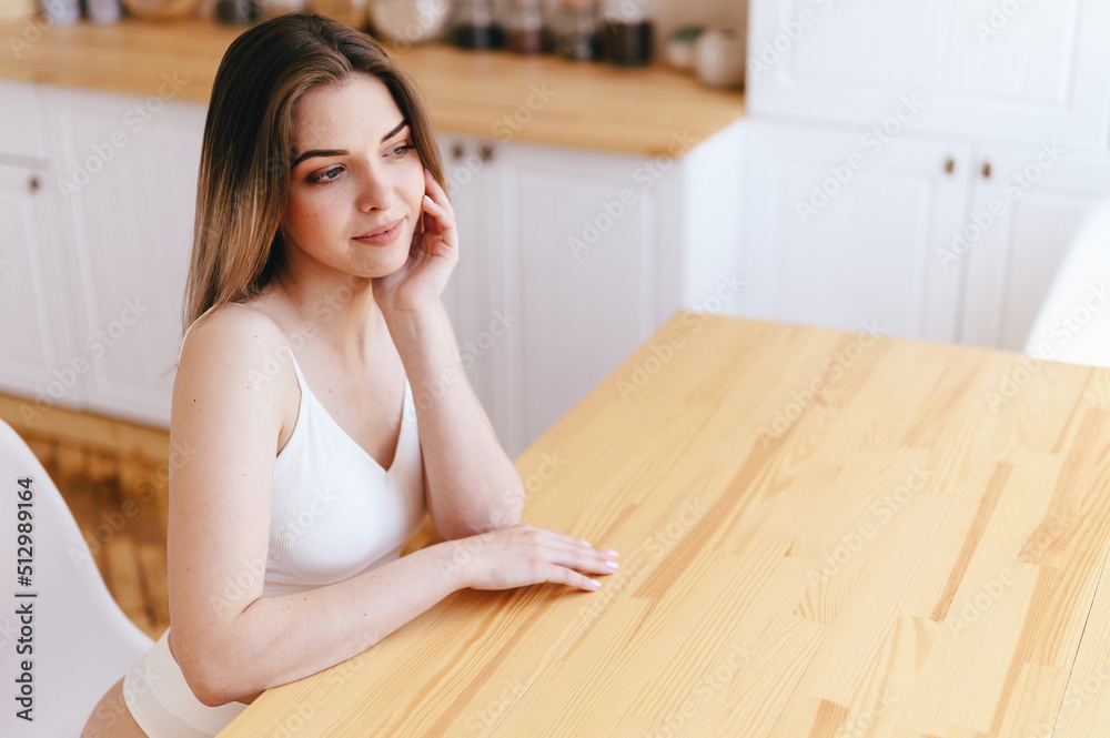 Lovely Young Woman in Smiling sits at Wooden Table. Girl Looks out Window, Meditate On coming Day Lovely Young Woman in Smiling sits at Wooden Table. Girl Looks out Window, Meditate On coming Day