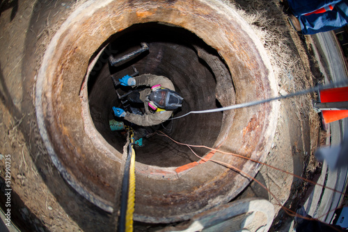 Worker in manhole installing cable photo