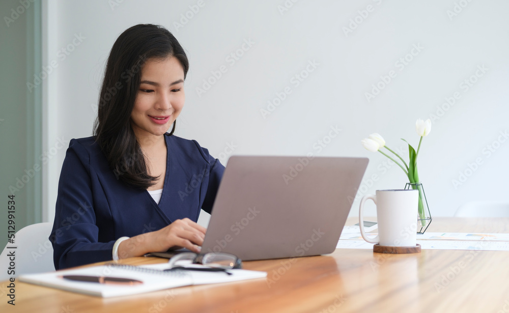 Young asian female office worker sitting in bright office and working on computer laptop.. Young asian female office worker sitting in bright office and working on computer laptop..