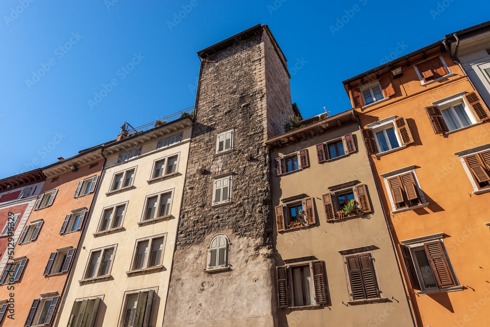 Close-up of a medieval tower and old houses in Trento downtown (via Rodolfo Belenzani), the main street of the city in the center. Trentino Alto Adige, Italy, Europe.