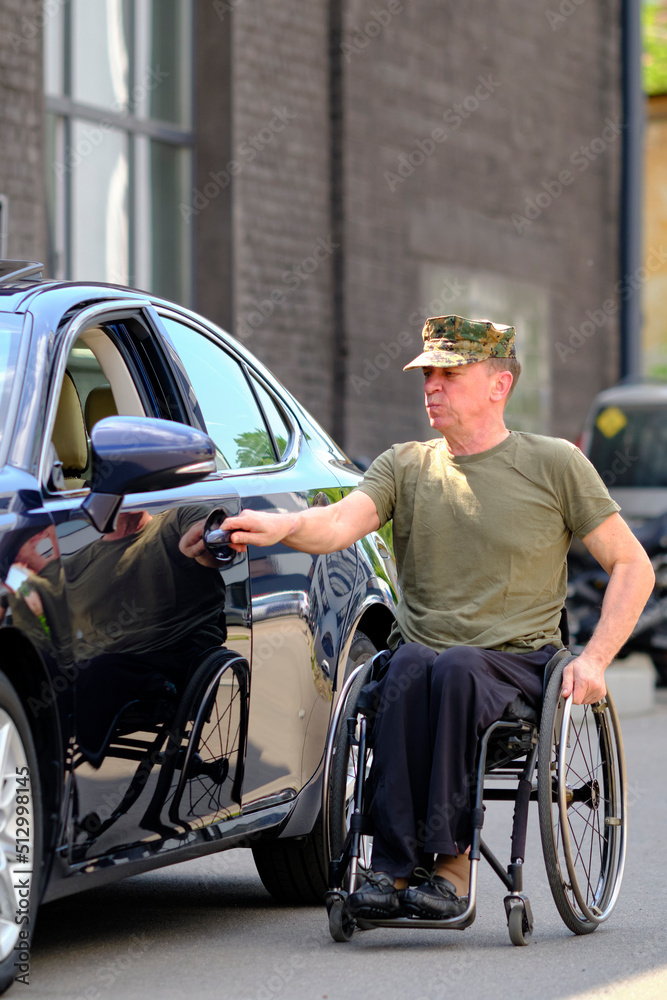 driver with disability, a man in a wheelchair holds his hand on the car door