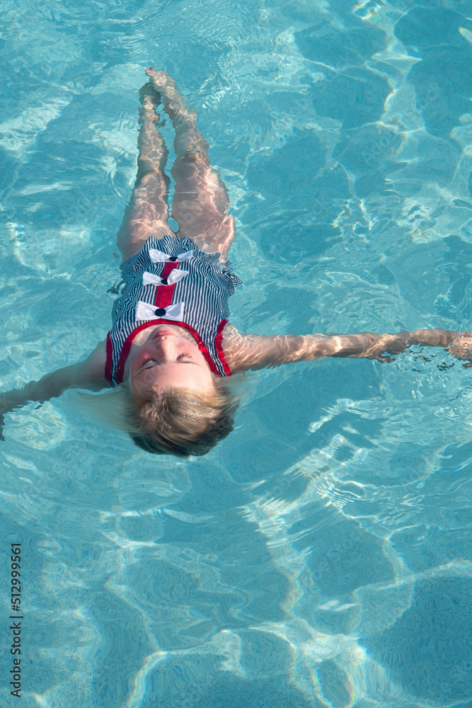 Young girl floats on her back in a swimming pool.