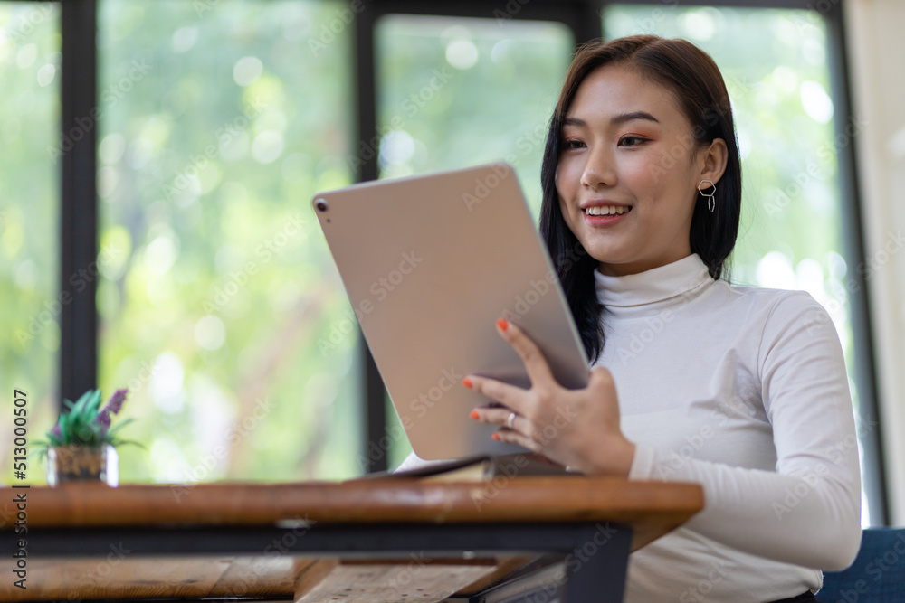 Attractive young Asian business woman wearing casual clothes is working on a tablet in the home office. Attractive young Asian business woman wearing casual clothes is working on a tablet in the home office.