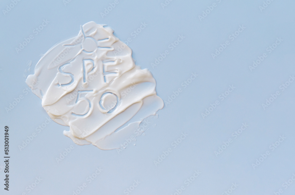 White cream texture on a blue background and SPF 50 text. The concept of skin protection, a banner with copy space. White cream texture on a blue background and SPF 50 text. The concept of skin protection, a banner with copy space.