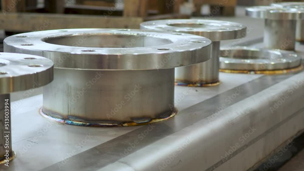 Shiny new stainless steel flanges welded on a square tube. Pan shot.