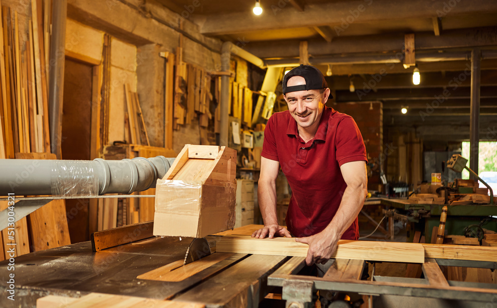 Professional carpenter in uniform works on a woodworking machine at the carpentry manufacturing Professional carpenter in uniform works on a woodworking machine at the carpentry manufacturing
