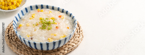 Delicious rice porridge congee with corn kernel and vegetables on white table background.