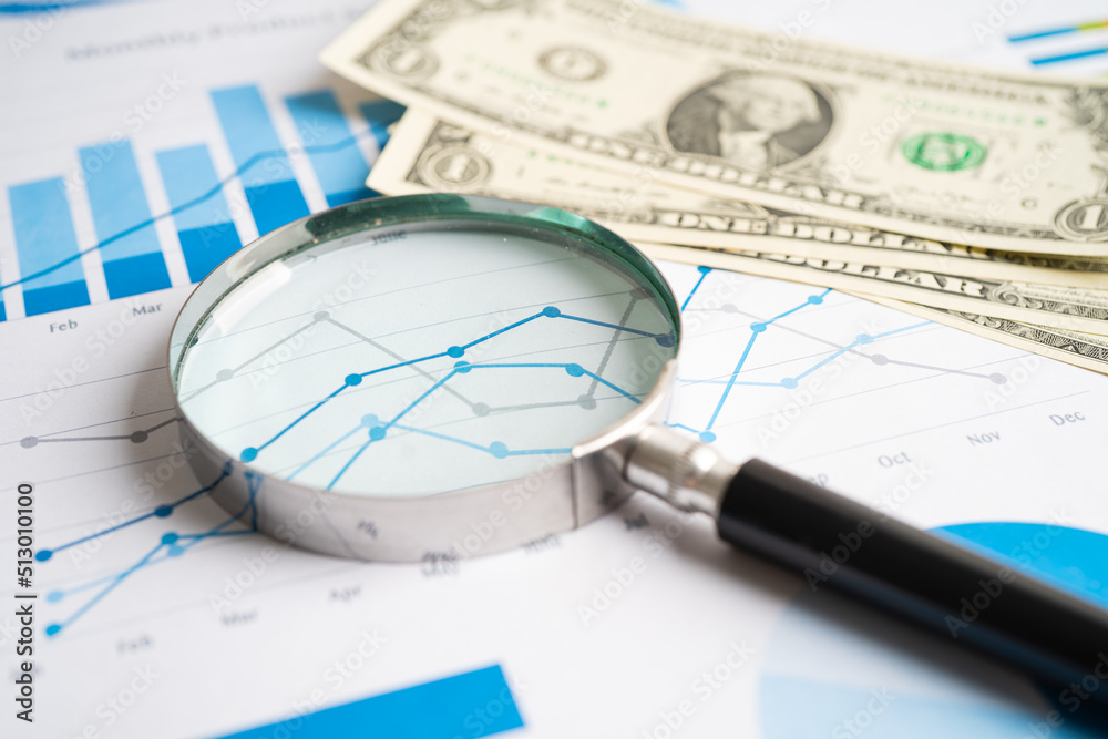 Magnifying glass with US dollar banknotes on charts graphs paper. Financial development, Banking Account, Statistics, Investment Analytic research data economy. Magnifying glass with US dollar banknotes on charts graphs paper. Financial development, Banking Account, Statistics, Investment Analytic research data economy.