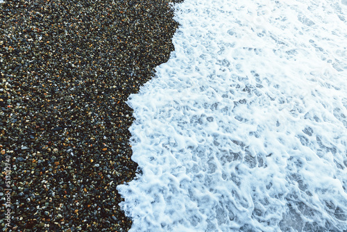 Seascape. Blue and gray pebbles on the beach. White sea waves. Skyline. Nature multicolored background.
