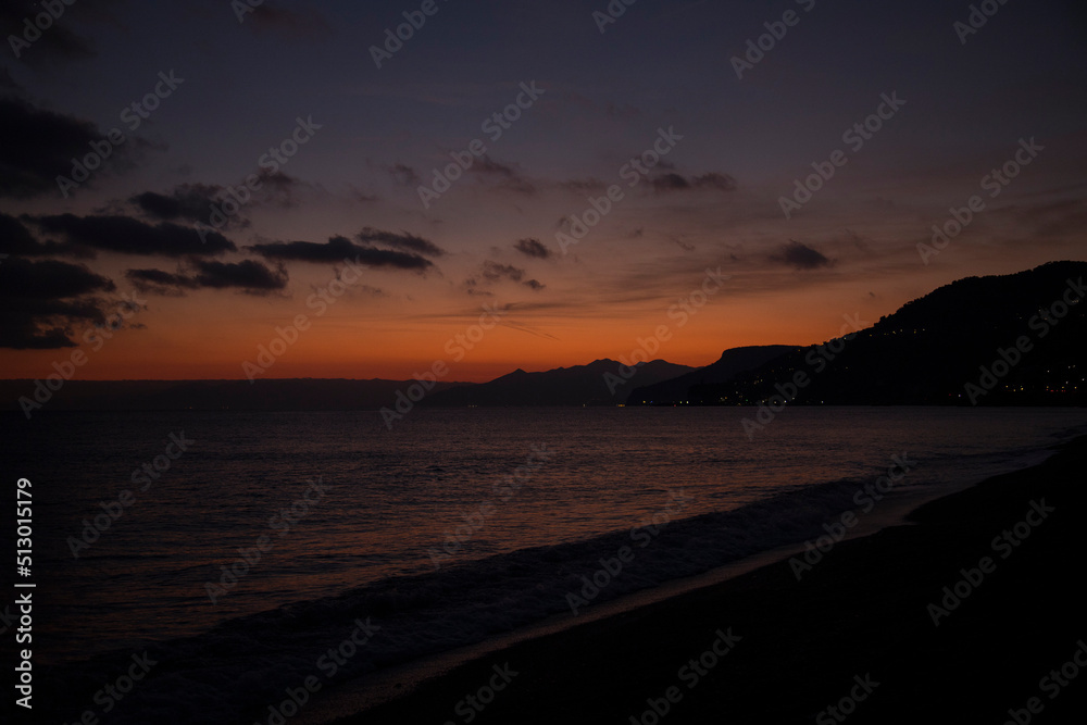 Sunset on the sea.
Seascape at sunset, with beach, orange sky, and distant lights of some countries.