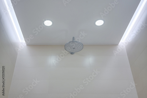 suspended ceiling with halogen spots lamps and drywall construction in bathroom with shower head photo