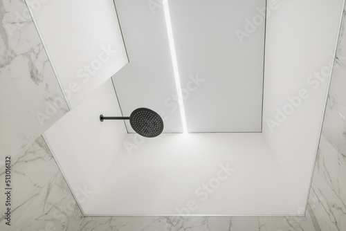 suspended ceiling with halogen spots lamps and drywall construction in bathroom with shower head photo