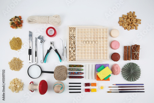 Tools, pliers, eyepiece, paints, pencils lined up on a white background
