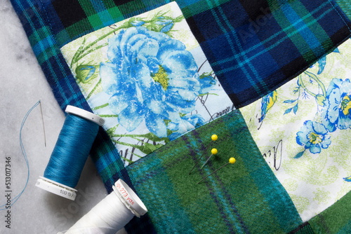 A sewing closeup of a quilted blanket with neddle and thread with blue and green squares. photo