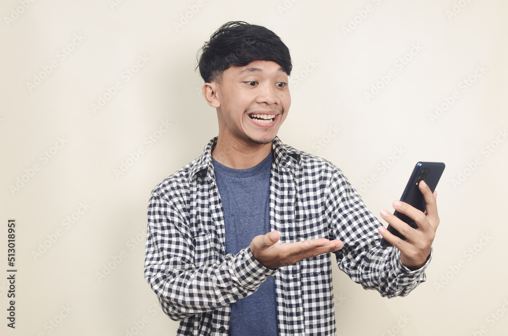 Closeup portrait of happy young Asian male model wearing plaid shirt while getting message on his phone Closeup portrait of happy young Asian male model wearing plaid shirt while getting message on his phone