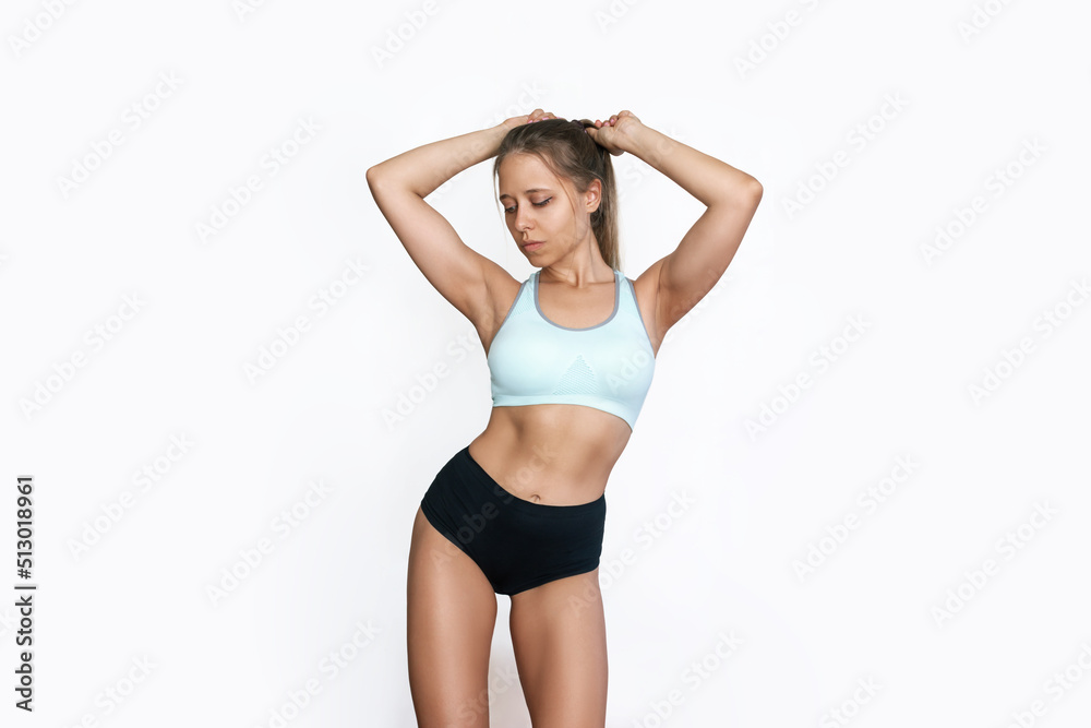 Young tanned fit woman in sports underwear demonstrating her slender figure  with toned abs on stomach isolated on white background. Result of fitness,  diet, healthy lifestyle. Female perfect body Stock-Foto | Adobe