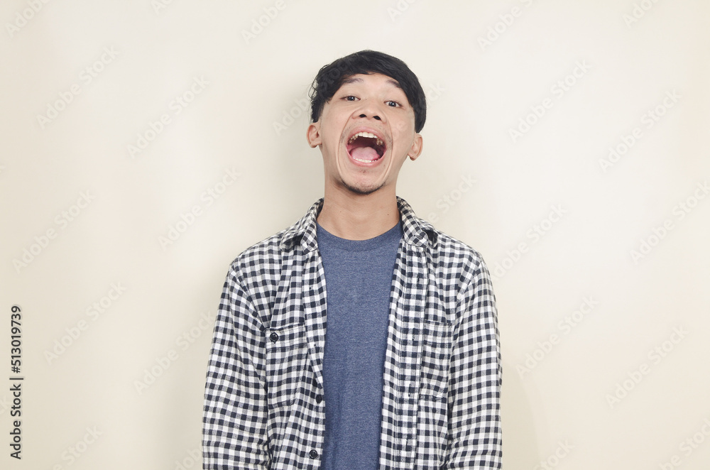 Excited young asian man shouting on isolated background Excited young asian man shouting on isolated background