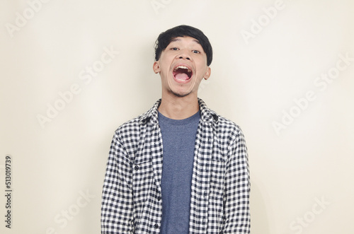 Excited young asian man shouting on isolated background