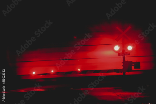 railway crossing at night. Red lights moving train action shot. 