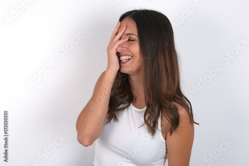 Charismatic carefree joyful young beautiful caucasian woman wearing white top over white background likes laugh out loud not hiding emotions giggling hear funny hilarious joke chuckling facepalm.