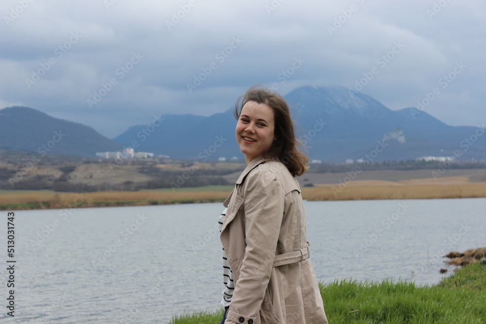 A joyful girl on the shore of a lake in the mountains, a smile and joy.