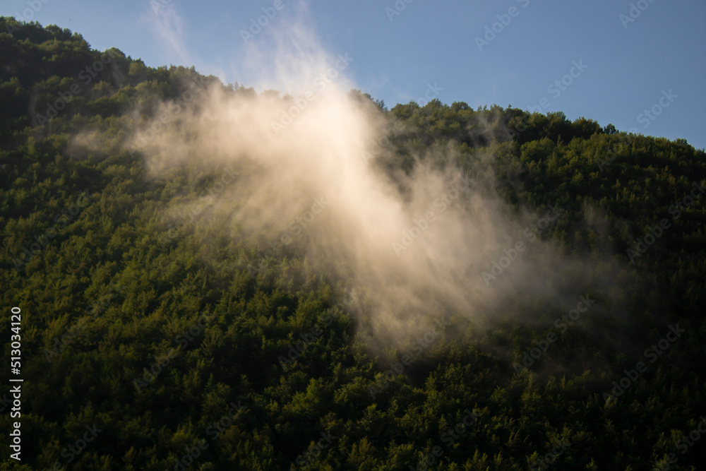 Clouds cascade down over the forest landscape on a beautiful summer day. Clouds cascade down over the forest landscape on a beautiful summer day.