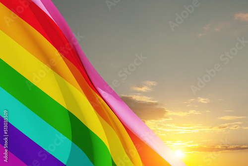 Waving LGBT pride flag on the blue sky, rainbow flag background. Multicolored peace flag movement.