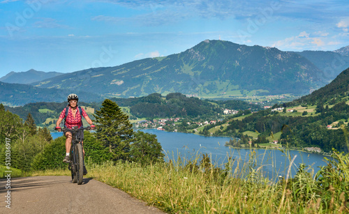 beautiful senior woman riding her electric mountain bike on the mountains above Lake Alpsee near Immenstadt, Allgau,Bavaria, Germany 