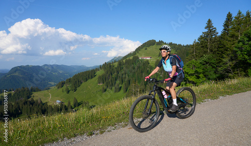 pretty senior woman riding her electric mountain bike in the Allgaeu mountains above Oberstaufen   Allgau Alps  Bavaria Germany 
