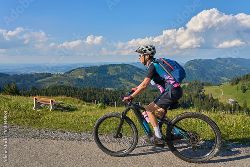 pretty senior woman riding her electric mountain bike in the Allgaeu mountains above Oberstaufen , Allgau Alps, Bavaria Germany 