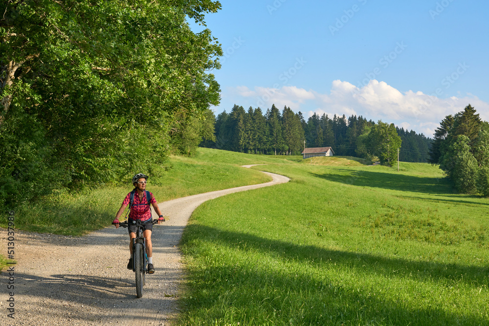 pretty senior woman riding her electric mountain bike in the Allgaeu mountains above Oberstaufen , Allgau Alps, Bavaria Germany
