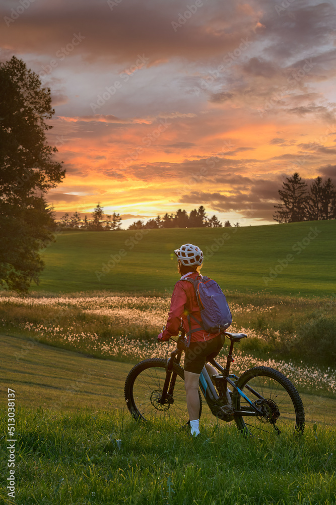active woman riding her electric mountain bike at sunset in the Bregenz  Forest mountains near Sulzberg, Vorarlberg, Austria Stock Photo | Adobe  Stock