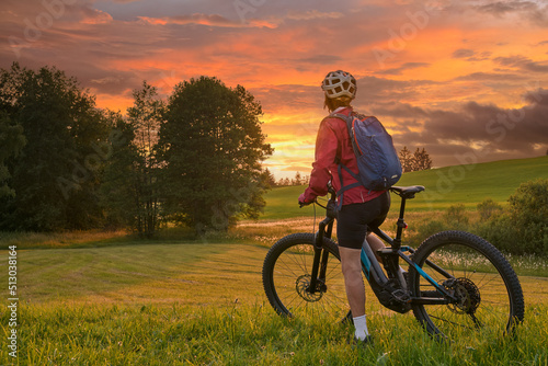 active woman riding her electric mountain bike at sunset in the Bregenz Forest mountains near Sulzberg, Vorarlberg, Austria
 photo