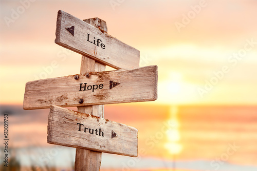 Fotografia life hope truth text quote on wooden crossroad signpost outdoors on beach with pink pastel sunset colors