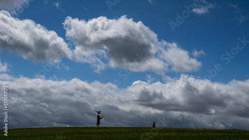 People silhouetted against a blue cloudy sky launching a kite on the Yorkshire coastline