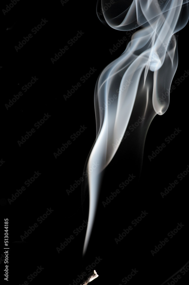 Puffs and curls of white smoke against a black background rising from a burning stick Puffs and curls of white smoke against a black background rising from a burning stick