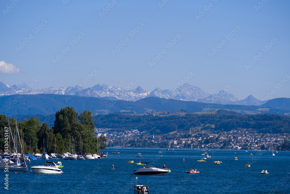 Scenic landscape with Lake Zürich, leisure boats and Swiss Alps in the background on a sunny summer day seen from City of Zürich. Photo taken June 11th, 2022, Zurich, Switzerland.