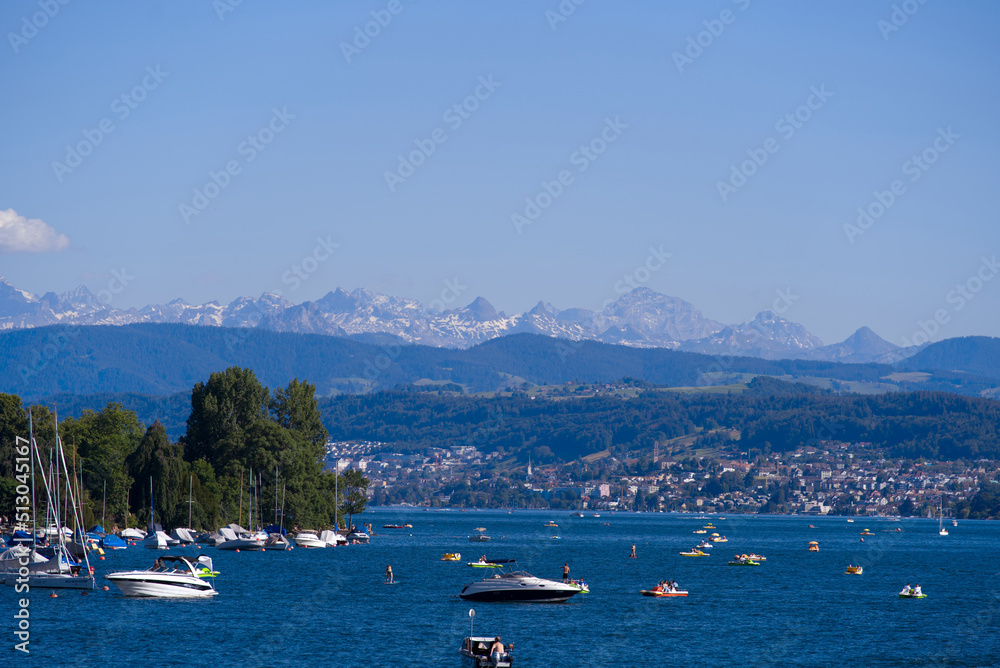 Scenic landscape with Lake Zürich, leisure boats and Swiss Alps in the background on a sunny summer day seen from City of Zürich. Photo taken June 11th, 2022, Zurich, Switzerland. Scenic landscape with Lake Zürich, leisure boats and Swiss Alps in the background on a sunny summer day seen from City of Zürich. Photo taken June 11th, 2022, Zurich, Switzerland.