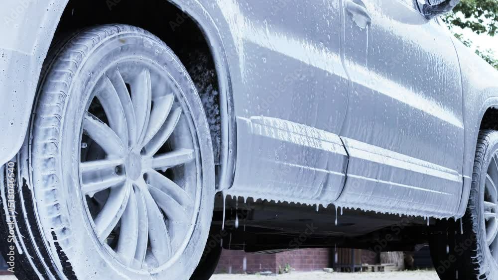 Washing the car with foam and water under high pressure at the car wash. Car washing concept.