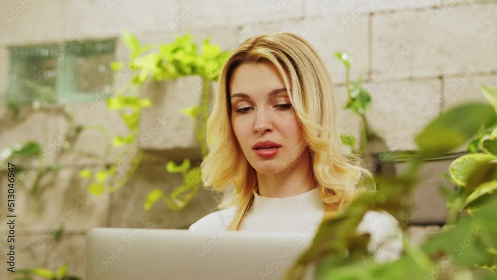Florist woman using laptop. Greenhouse worker, female botanist close-up, small business owner. Gardener working in flower shop, plant store. Florist woman using laptop. Greenhouse worker, female botanist close-up, small business owner. Gardener working in flower shop, plant store.