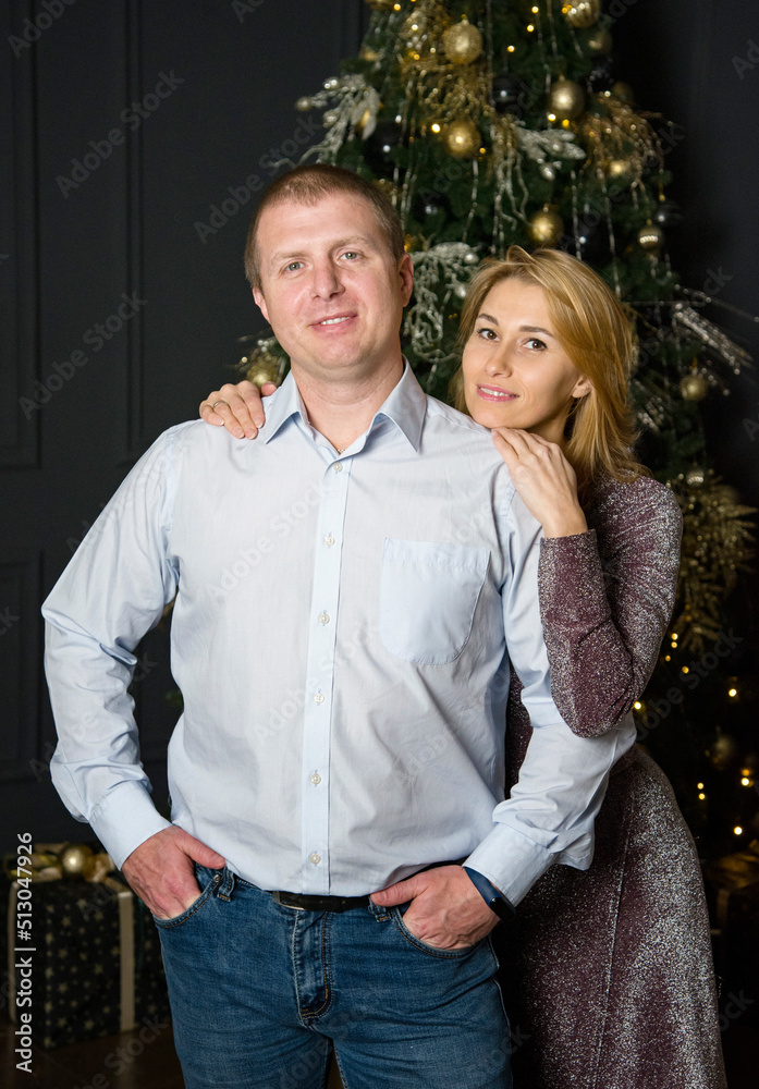 The lovely couple in love embracing near christmas tree